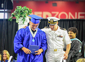 Graduate hugged by brother in Navy whites